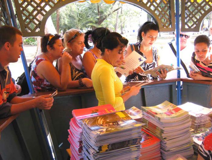 Libros en un quiosco y varias personas mirando libros.