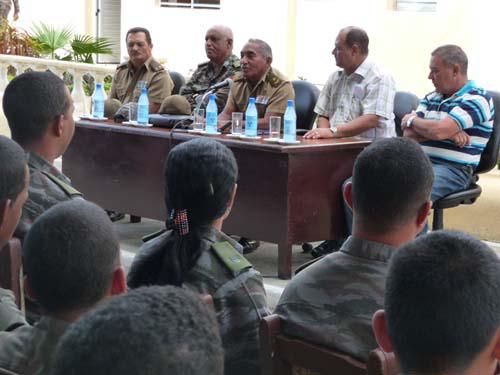 Arnaldo Tamayo en una mesa con cuatro personas más, hablándole a una audiencia sentada frente a él.