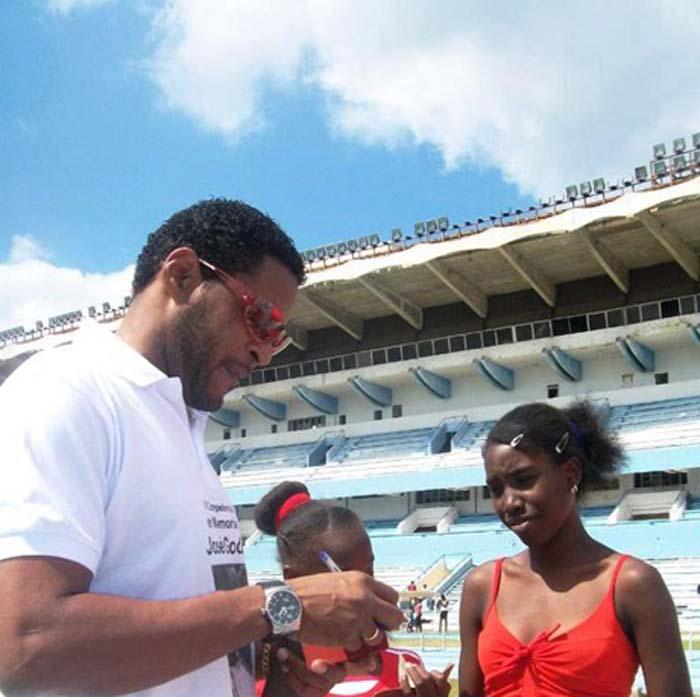 Javier Sotomayor con dos niñas en un estadio.