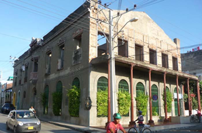 Edificio de dos plantas, un automovil transitando por una calle.
