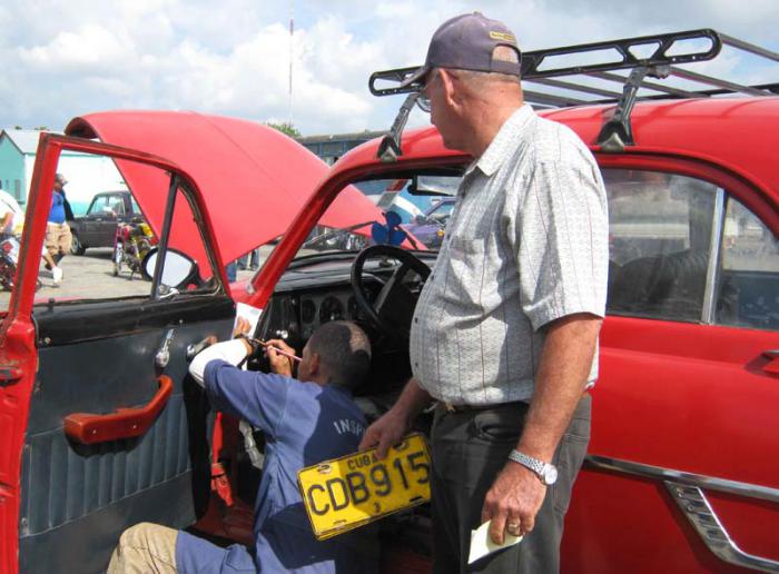 El inspector Carlos Manuel Guerra Milanés revisa el  número de la carrocería de uno de los vehículos. 