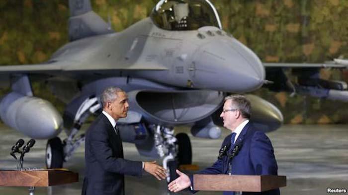 El presidente Barack Obama estrecha la mano a su homólogo polaco, Bronislaw Komorowski, con el fondo de un avión caza F-16. 