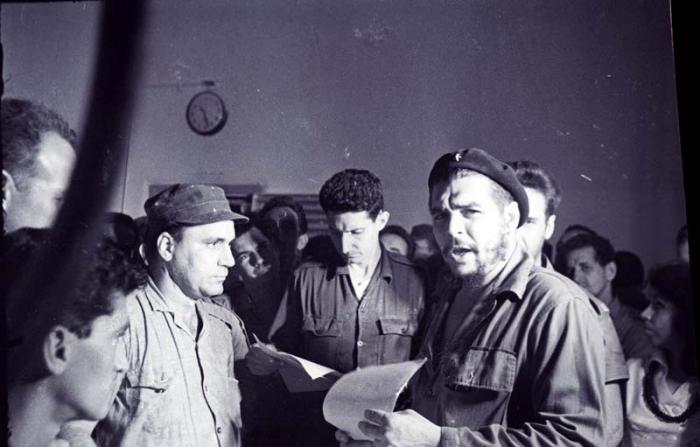 El Comandante Ernesto Che Guevara realiza una jornada de trabajo voluntario en los Molinos de Trigo José A. Echeverría, en Regla, y cose el saco 100 000. En el centro el Comandante Juan M.Castiñeiras y detrás del Che, el capitán Jesús Suárez Gayol. 