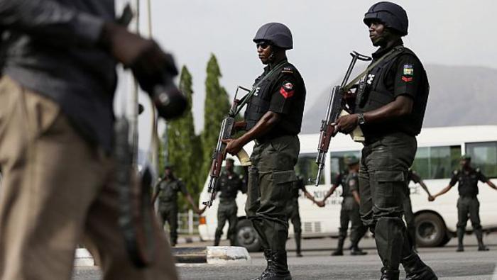 Police officers patrol near a journalist during a protest by the Abuja wing of the 