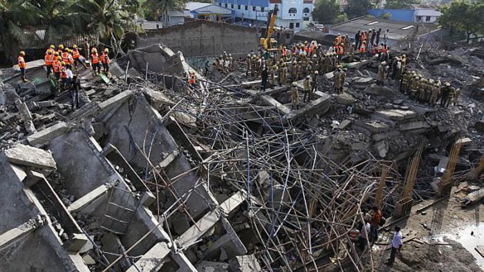 Rescuers search for workers believed buried in the rubble of a building that collapsed on the outskirts of Chennai, India, Sunday, June 29, 2014. Police said dozens of workers have been pulled out so far and the search is continuing. (AP Photo/Arun Sankar K)