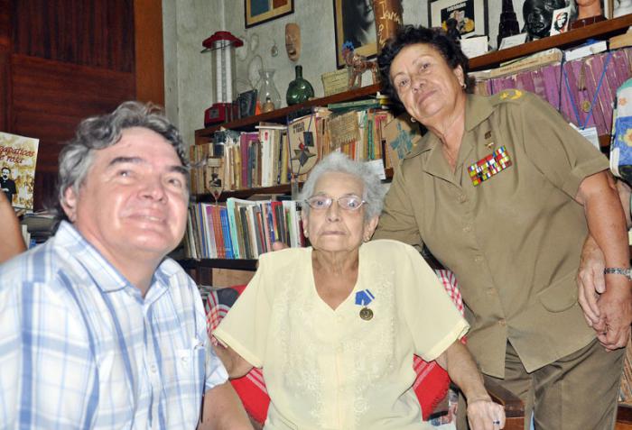 Julián González Toledo (i), ministro de cultura; Nidia Yolanda Sarabia Hernández (c), periodista e investigadora cubana, y Teté Puebla (d), general de brigada, durante la imposición de la medalla Alejo Carpentier a Nidia, en casa de Nidia, Vedado, La Habana, Cuba.