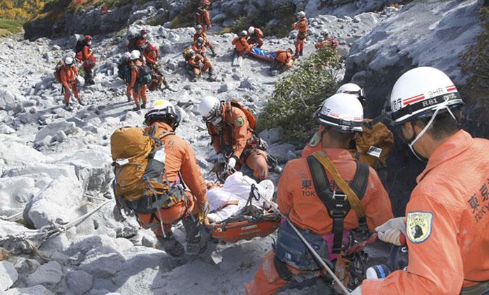 Firefighters carry a hiker during rescue operations on Mount Ontake, which straddles Nagano and Gifu prefectures, central Japan, in this handout photograph released by Tokyo Fire Department and taken September 28, 2014. The death toll from Japan's worst volcanic eruption in decades is likely to rise to around 46 after as more victims were discovered on the ash-covered summit, media said on Wednesday. Picture  taken September 28, 2014.   REUTERS/Tokyo Fire Department/Handout via Reuters (JAPAN - Tags: DISASTER ENVIRONMENT) ATTENTION EDITORS - THIS PICTURE WAS PROVIDED BY A THIRD PARTY. REUTERS IS UNABLE TO INDEPENDENTLY VERIFY THE AUTHENTICITY, CONTENT, LOCATION OR DATE OF THIS IMAGE. FOR EDITORIAL USE ONLY. NOT FOR SALE FOR MARKETING OR ADVERTISING CAMPAIGNS. NO SALES. NO ARCHIVES. THIS PICTURE IS DISTRIBUTED EXACTLY AS RECEIVED BY REUTERS, AS A SERVICE TO CLIENTS JAPAN-VOLCANO/