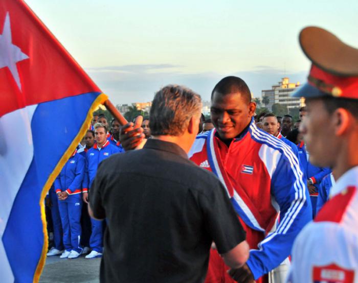 Miguel Díaz-Canel, miembro del Buró Político y primer vicepresidente del Consejo de Estado y Ministros, le entrega la enseña nacional al campeón olímpico y mundial, Mijain López.