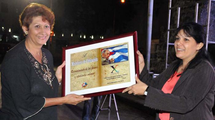 Yuniasky Crespo Baquero, entrega reconocimiento a Ena Elsa Veláz­quez por los significativos lo­gros del Ministerio de Educación. 