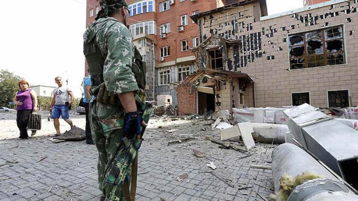 An armed pro-Russian separatist stands in front of damaged buildings following what locals say was shelling by Ukrainian forces in Donetsk August 7, 2014. The Ukrainian government said on Thursday it was suspending a ceasefire with separatist rebels at the crash site of the Malaysian airliner after an international recovery mission had been halted. REUTERS/Sergei Karpukhin (UKRAINE - Tags: POLITICS CIVIL UNREST MILITARY) Ucrania-ataques