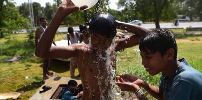 Pakistani youth cool themselves with water during a heat wave in Islamabad on June 21, 2015. At least 17 people have died as a heat wave has gripped the country, local media reported.  AFP PHOTO /  Farooq NAEEM