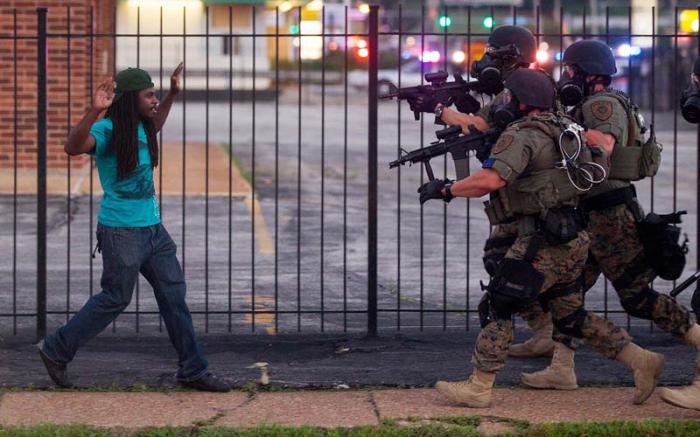 A man backs away as law enforcement officials close in on him and eventually detain him during protests over the death of Michael Brown, an unarmed black teenager killed by a police officer, in Ferguson, Mo., Aug. 11, 2014. The Federal Bureau of Investigation said on Monday that it had opened an inquiry into the weekend shooting of Brown. (Whitney Curtis/The New York Times)
