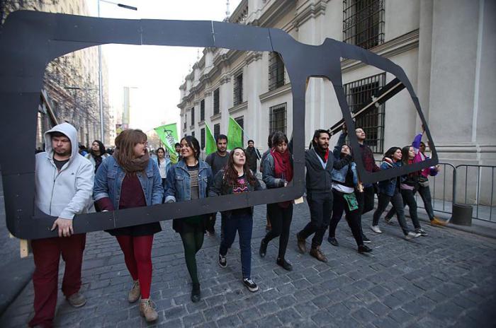 Un grupo de jóvenes marcha cargando una representación de los lentes del presidente Salvador Allende en un homenaje a la víctimas del golpe de Estado militar de Augusto Pinochet 
