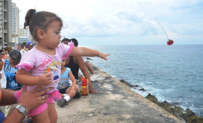 Niña echa una flor al mar por el aniversario 55 de la desaparición de Camilo Cienfuegos.