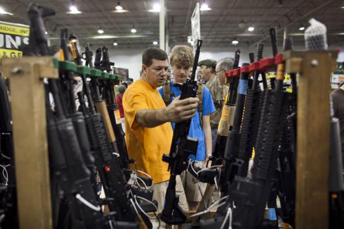 Un adolescente junto a su padre observan un arma que posiblemente compren. En Estados Unidos se ha disparado la compra de armas por temor a un mayor control.