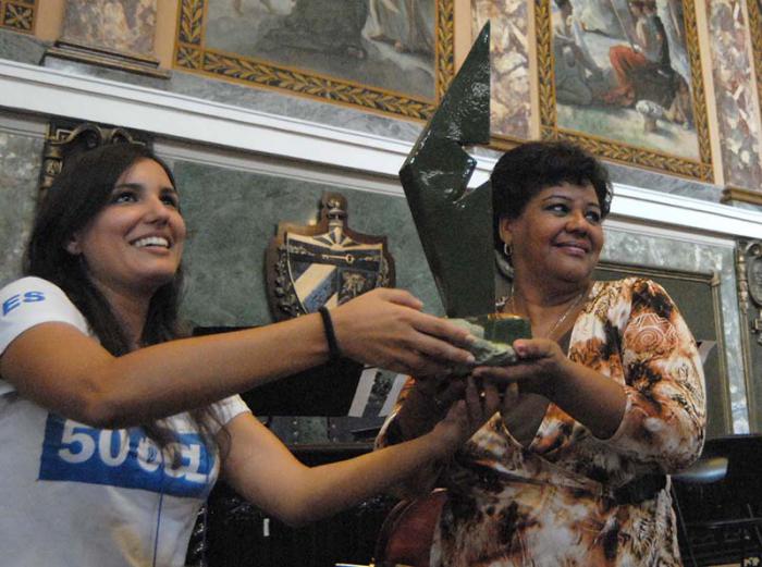 Acto Central por el 50 aniversario de la OCLAE. Entrega de la obra plástica de regalo por los 90 años del  Comandante Fidel Castro. Entrega:  Heydi Villuendas (Presidenta de la OCLAE) a Olga Lidia Tapia ( Miembro del Secretariado del Comite Central del Partido)