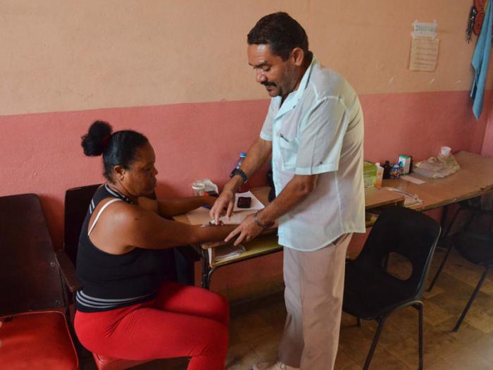 El enfermero Alfredo Jesús atiende a una paciente durante una entrevista en la escuela convertida en albergue para evacuaos por el huracán Matthew, Baracoa.