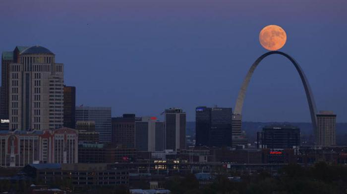 La luna se eleva más allá del arco en St. Louis.