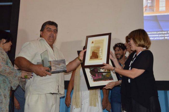 Gladys Collazo (derecha)  entrega el premio a Orelve Calero Pozo, proyectista principal de la restauración de la casa natal de Abel Santamaría. Foto: José Raúl Suárez Quevedo.
