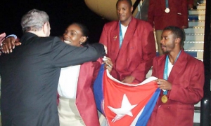 Fidel abraza a Mireya Luis, capitana del equipo Cuba, al regreso de la delegación de los Juegos de Sidney 2000, donde el voli (f) ganó su tercera presea de oro olímpica consecutiva. A la derecha, el saltador Iván Pedroso, y detrás el boxeador Félix Savón.