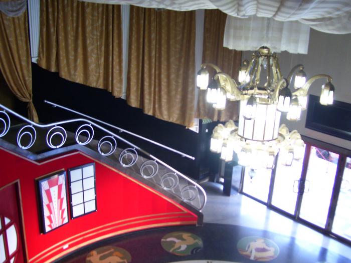 Elegantes escaleras curvilíneas ascienden a pequeñas salas. Podemos observar además, la hermosa lámpara que ilumina el vestíbulo