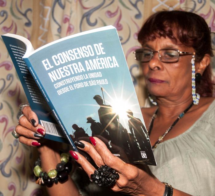 Trabajadora del periódico granma leyendo el libro El consenso de nuestra América