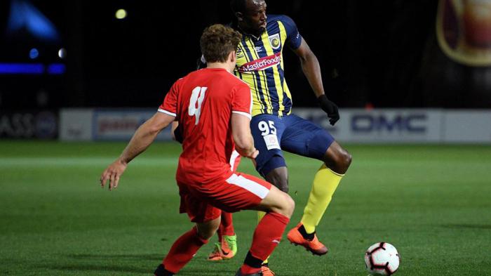 El exatleta jamaicano Usain Bolt con la camiseta de los Mariners, se enfrena a Jai McNamara, del Central Coast Select XI 