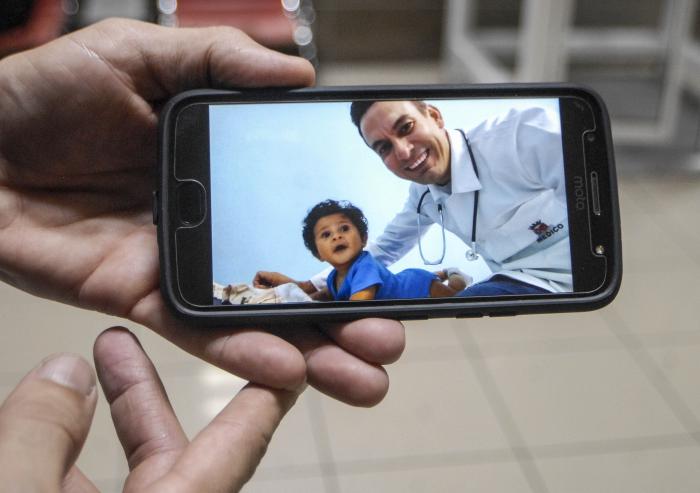 Recibimiento a Médicos Cubanos  procedentes de Brasil en la terminal nro.3 del aeropuerto José martí.30 de Noviembre.Doctor muestra una instantanea donde aparece con un niño brasileño que es su paciente