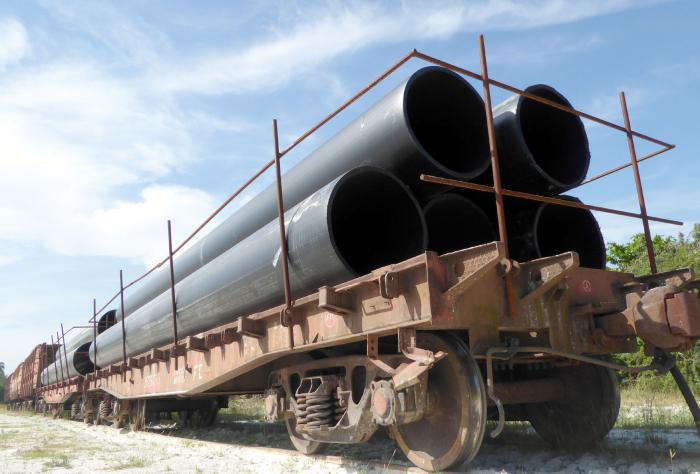 Una locomotora  arrastra varias planchas o góndolas y cada una carga cinco tubos de mil milímetros de diámetro y 12 metros de longitud. Una rastra solo lleva tres unidades.