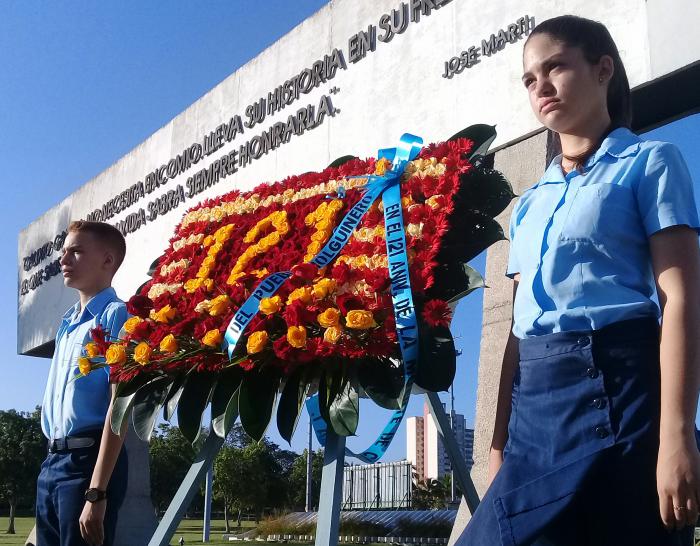 La ofrenda floral colocada en nombre del pueblo cubano es escoltada por estudiantes.