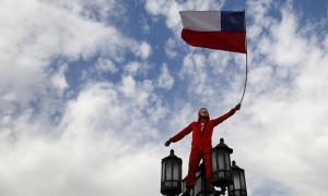 Un manifestante vestido como en ‘La Casa de Papel’ sostiene una bandera chilena 
