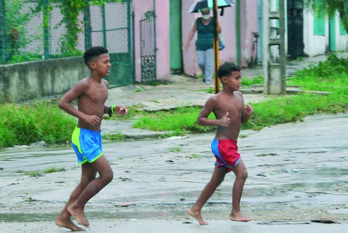 Proteccion contra el coronavirus ,niÃ±os en la calle  bajo la lluvia.