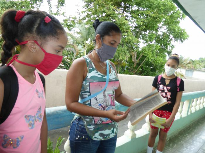 A petición de Liz Alejandra Belón Harrosay -a la izquierda- la bibliotecaria le ayuda a profundizar en un texto de historia