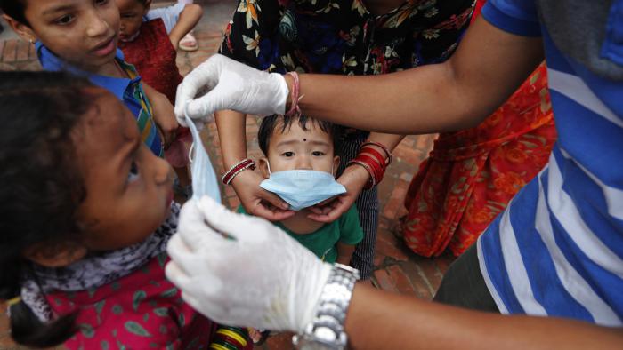 Un voluntario proporciona gratuitamente máscaras faciales a los niños asistentes a un festival en Nepal. 25 de julio de 2020.