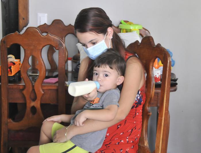 Proteccion contra el coronavirus,madre dandole el biberon de lehe al niño.