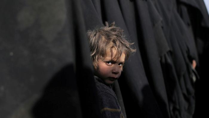 Un niño espera con su madre mientras hacen cola en busca de ayuda humanitaria y médica, en Deir ez-Zor (Siria), 5 de marzo de 2019.