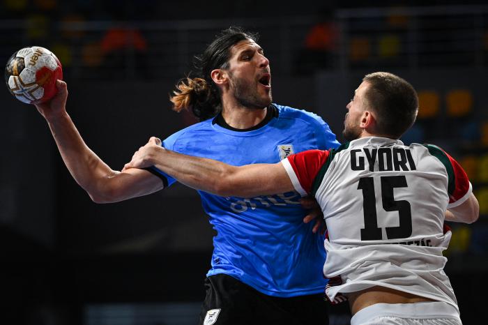 Uruguay's right back Maximo Cancio (L) fights for the ball with Hungary's centre back Matyas Gyori during the 2021 World Men's Handball Championship match between Group A teams Hungary and Uruguay at the 6th of October Sports Hall in 6th of October city, a suburb of the Egyptian capital Cairo on January 17, 2021. (Photo by Anne-Christine POUJOULAT / POOL / AFP)