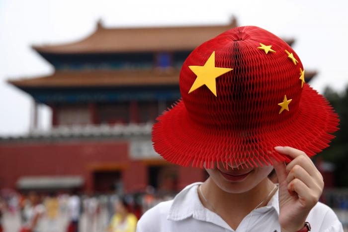 A women wears a bright red hat, covered with yellow stars in the style of the People's Republic of China's national flag, also known as the Five-star Red flag as she visits the Forbidden City in Beijing, China, on Thursday, July 28, 2016. As China's travel market takes off, all eyes should be on the country's roughly 400 million millennials, who will drive spending on airfare, hotels, theme parks, casinos and cruises. Photographer: Luke MacGregor/Bloomberg