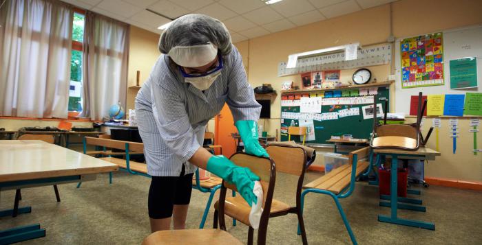 Una trabajadora desinfecta un aula de clases en Francia