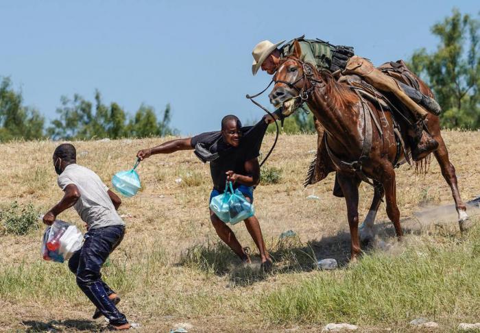 Un agente de la guardia fronteriza de Estados Unidos a caballo intenta evitar que un migrante haitiano ingrese a un campamento a orillas del Río Grande