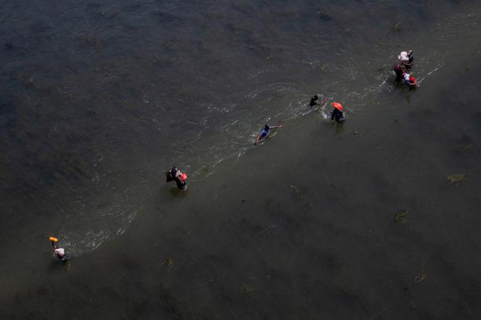 Varios migrantes que buscan refugio en Estados Unidos cruzan el río Bravo de regreso a Acuña, México, mientras otros regresan a los Estados Unidos con suministros

REUTERS