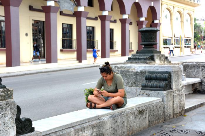 Paseo del Prado en La Habana. Muchacha conectada con su celular.