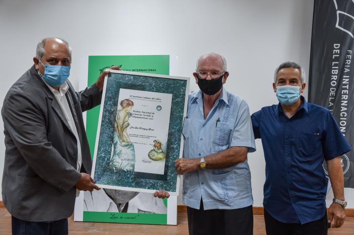El Ministro de Cultura Alpidio Alonso y el presidente del Instituto Cubano del Libro hacen entrega del reconocimiento al destacado economista. Foto Ariel Cecilio Lemus.