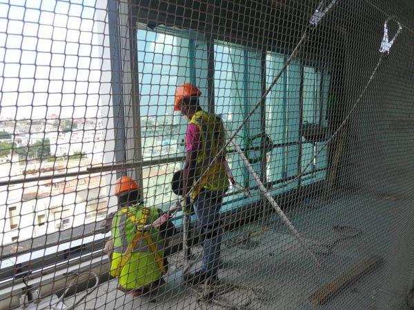 Obreros con cables de seguridad y la malla