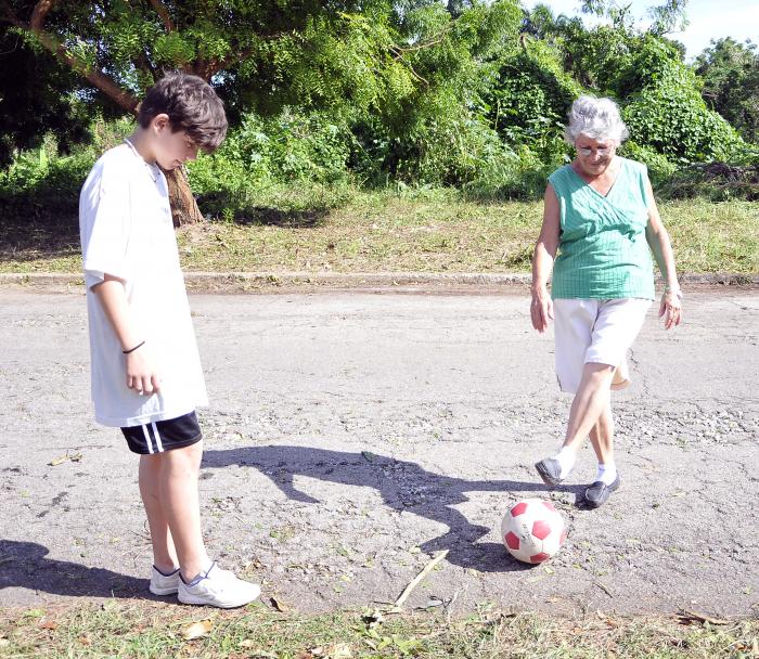 Abuela jugando fubol en la calle.