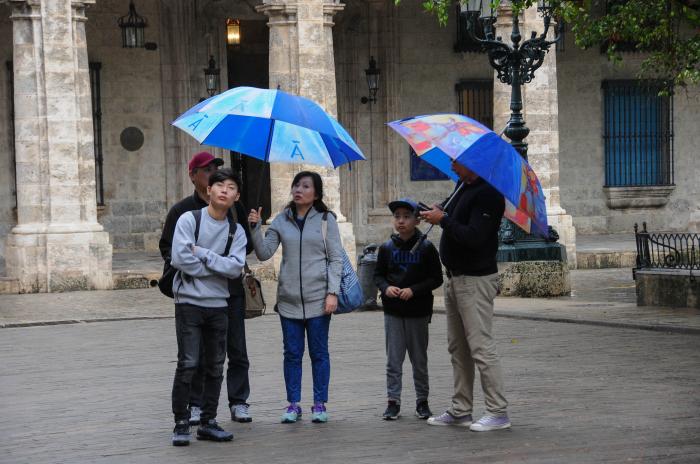 Turistas bajo la lluvia recorriendo la Plaza de Armas, en el casco histórico en la Habana Vieja.
