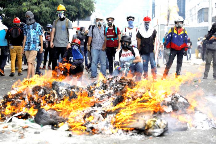 Opposition supporters stand in front of a fire during clashes with riot police at a rally against President Nicolas Maduro in Caracas, Venezuela May 3, 2017. REUTERS/Carlos Garcia Rawlins