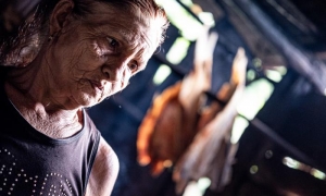 Señora con pescado ahumado detrás