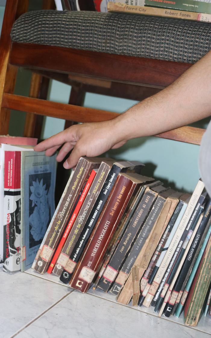 Hay libros sobre los bancos, sobre algunas mesas, en estantes, en el suelo.