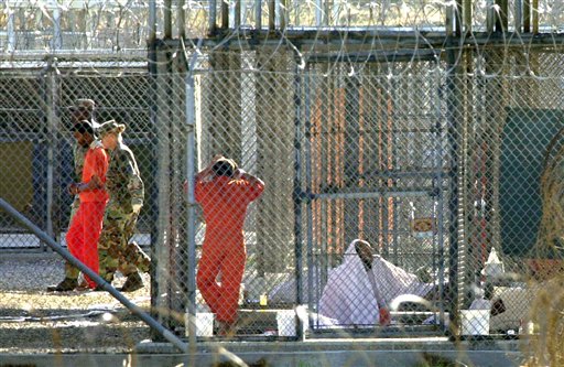 Una foto darchivio del 15 marzo 2002 mostra un prigioniero del Campo Rayos X, scortato dalle  guardie, mentre altri reclusi sono nelle loro celle nella   Base Navale della Baia di Guantnamo, in Cuba. (Foto AP/Tomas van Houtryve)
